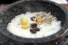 cooked rice sprinkled with four pieces of dried grape and cooked three chestnut in a black stone pot